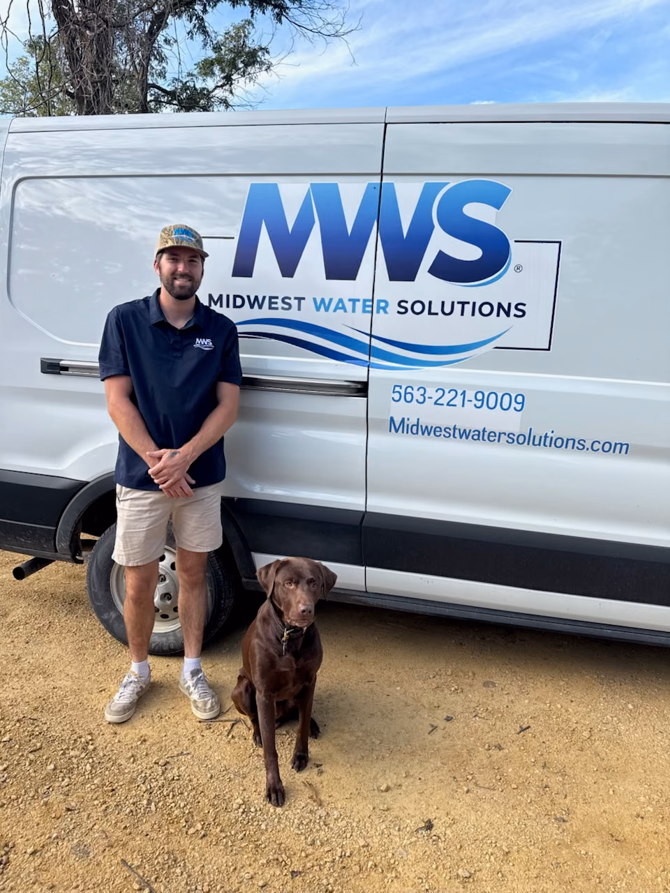 Midwest Water Solutions team member and a chocolate Lab beside the company service van