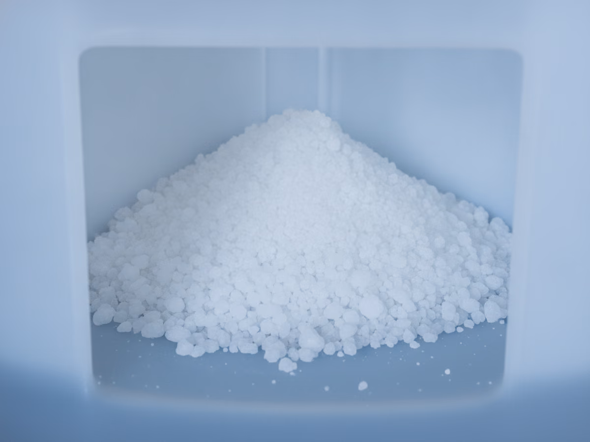 Close-up of white salt pellets heaped in a brine tank
